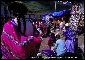 Peru. Marketplace at Andes town of Pisac, in Sacred Valley of Urubamba River, below Cusco. Woman with baby inside manta. Native crafts and markets