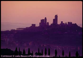 San Gimignano, famous turretted hill town of Tuscany, Italy, at dawn, with cypress trees silhouetted and echoing the towers. Italian architecture and culture.