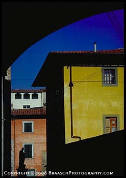 narrow street in Pisa, Italy, with strong colored walls and statue of regional hero. Tuscany. Italian architecture. Colors